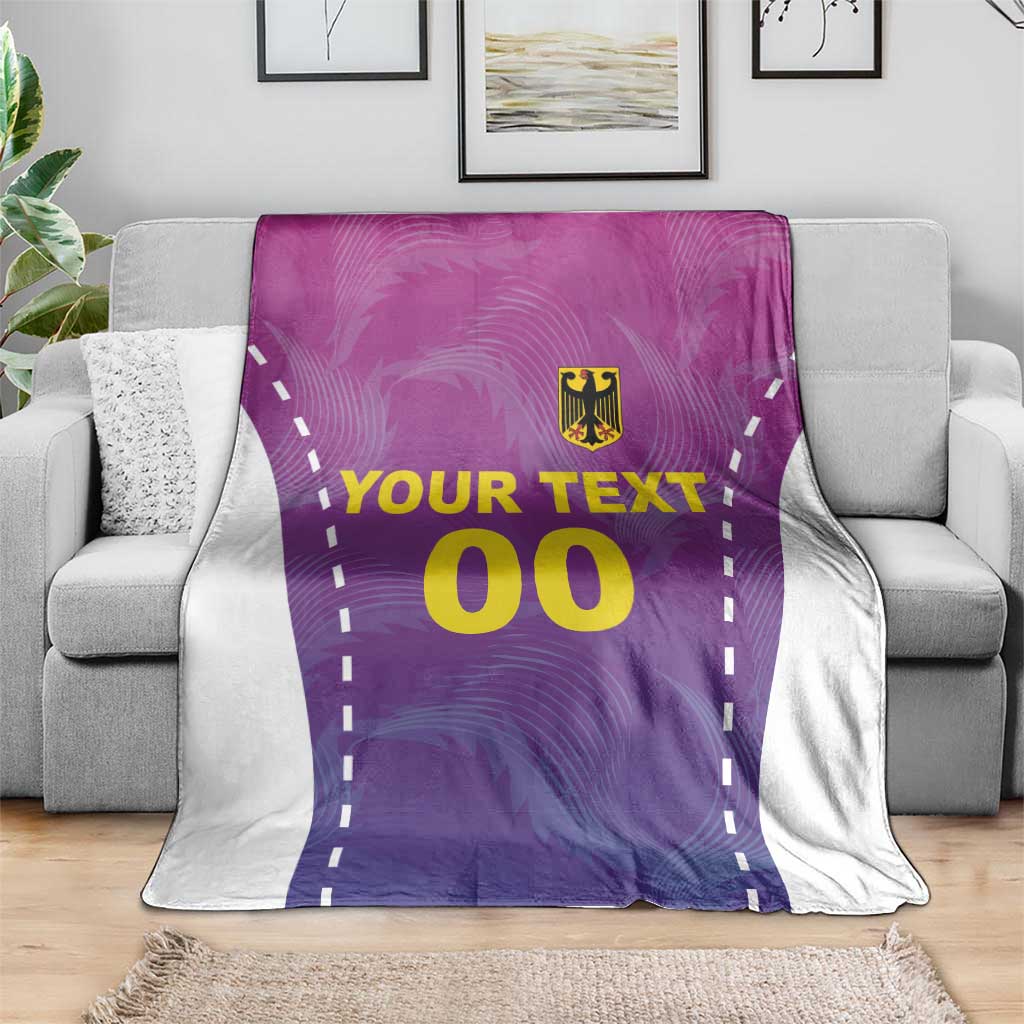 Purple football blanket with white border, gold crest, “YOUR TEXT” and “00” on sofa