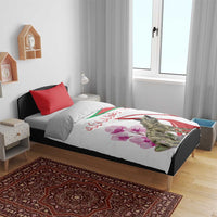 White bedding set on a bed with red pillowcases; hyena and pink flower print on duvet.