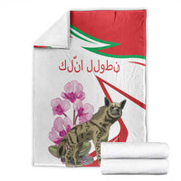 White blanket set with rolled white stacks; red-green stripes, pink cyclamen blooms, hyena print.