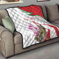 Quilt laid across a sofa with white quilting, red diagonal stripe, green border, purple flowers, hyena