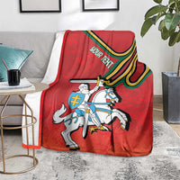 Red coat of arms blanket, folded on sofa, with knight and striped banner print