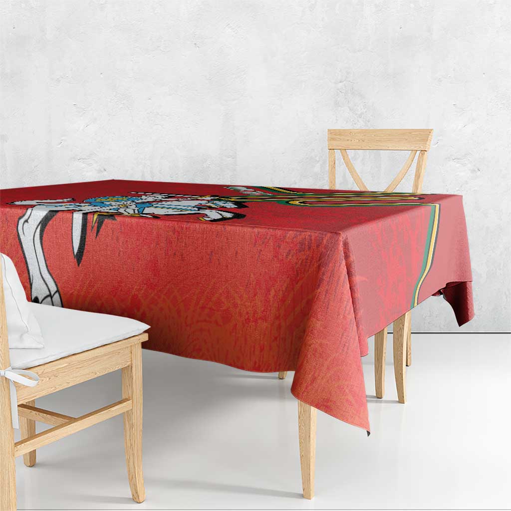 Red coat of arms tablecloth draped over a wooden table, hem and corner visible.