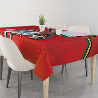 Red coat of arms tablecloth on dining table with chairs and small centerpiece items.