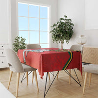 Red coat of arms tablecloth on dining table with multiple chairs in a bright room.