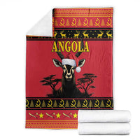 Red Angola blanket with antelope portrait and gold border, stacked white towels beside it