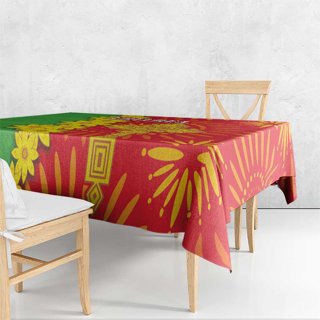 Square folk-pattern tablecloth draped over dining table in red and green with yellow motifs