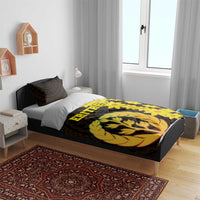 Black bedding set on bed; yellow floral and tree emblem design on duvet and pillow covers