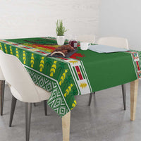 Green tablecloth with jungle-style prints and border, set with plates and small decor