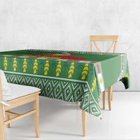Green tablecloth with banana and geometric trim pattern, draped over a dining table