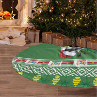 Green fabric tree skirt, white border fringe, patterned holiday artwork and bird figure
