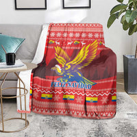 Red Feliz Navidad blanket on couch with condor wings design and holiday border