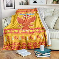 Yellow Christmas blanket on a sofa bed, with Merry Christmas script and red eagle emblem.