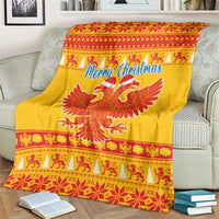 Yellow Christmas blanket on a couch arm, with Merry Christmas lettering and red eagle graphic.