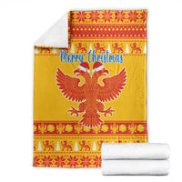 Yellow Christmas blanket folded with white stacks, featuring Merry Christmas and red double-headed eagle.