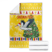 Yellow Christmas blanket folded, featuring stork, pine tree, and “Craciunun Fericit” text
