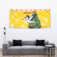 Yellow Christmas tapestry featuring a stork with Santa and a decorated Christmas tree