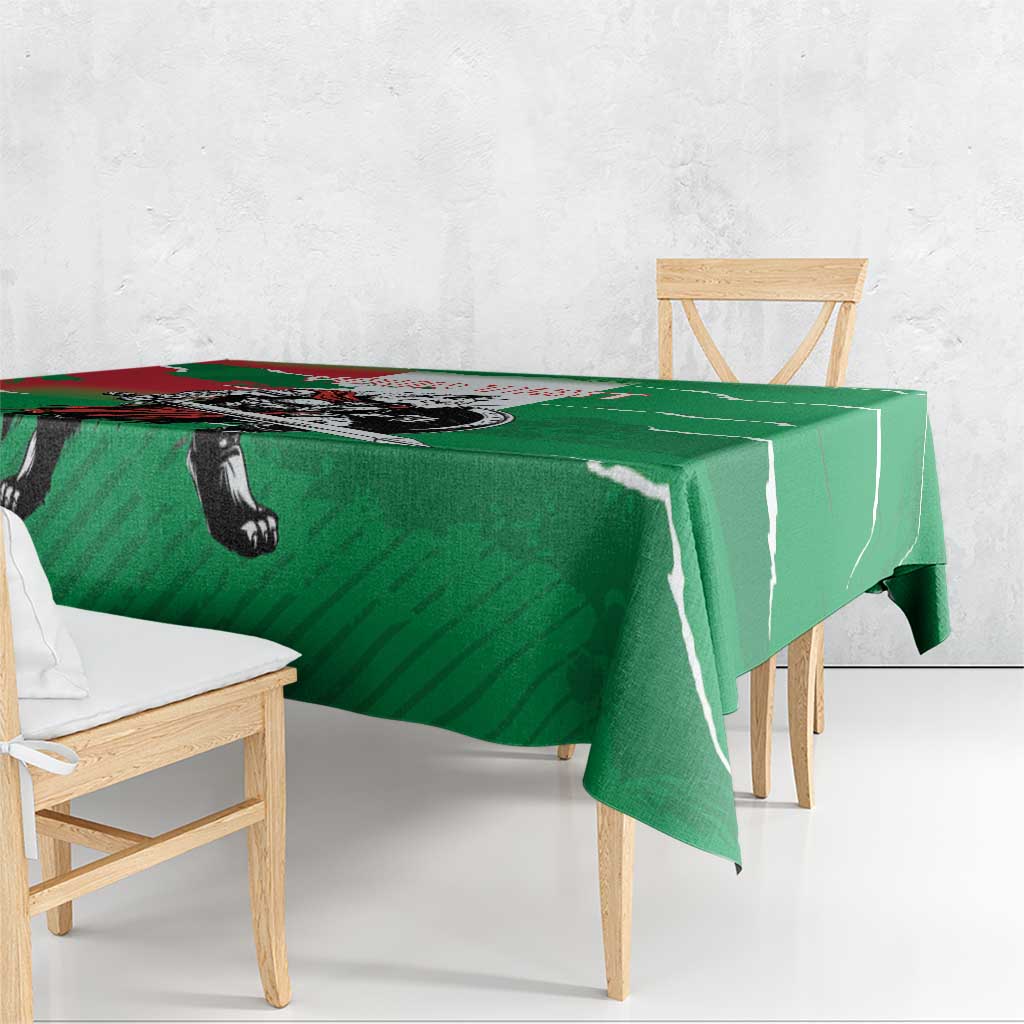 Green tablecloth with wolf warrior grunge print and hanging fabric over wooden chairs.