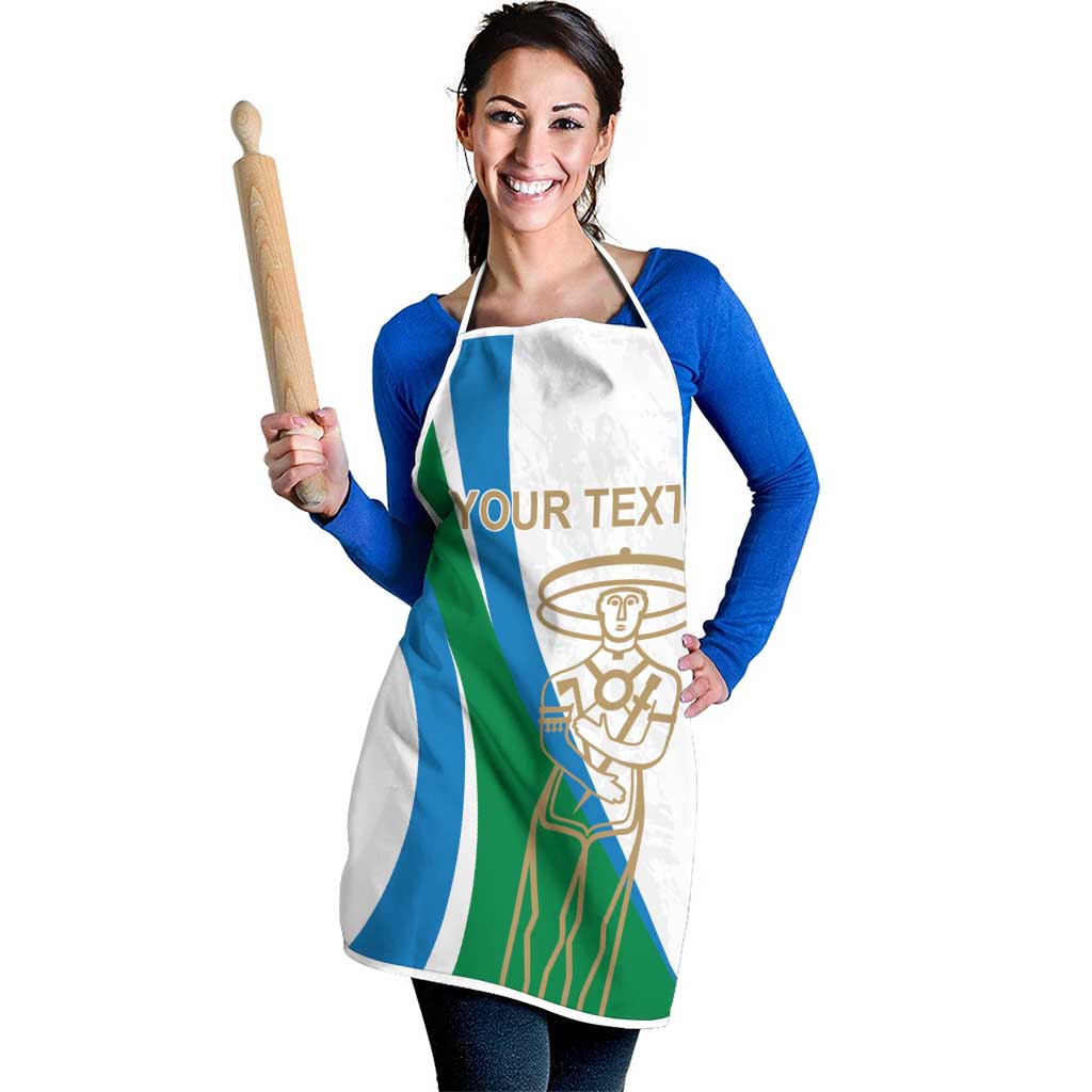 White apron with blue/green stripe panel and gold chef emblem; neck and waist straps