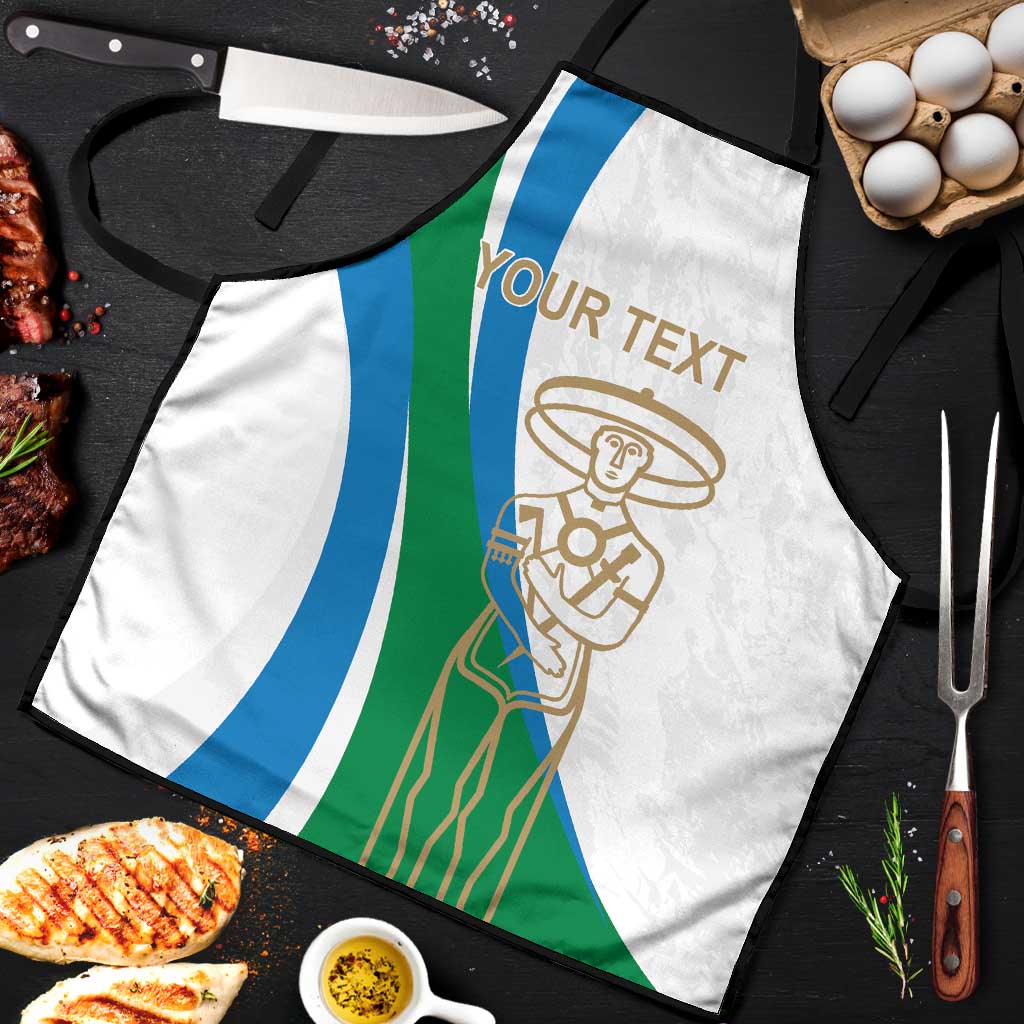 White apron close-up with blue/green stripes and gold chef emblem; tied neck and waist