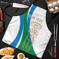 White apron close-up with blue/green stripes and gold chef emblem; tied neck and waist