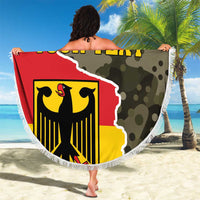 Round beach blanket with fringe edge, red/yellow German coat-of-arms shield over green camo