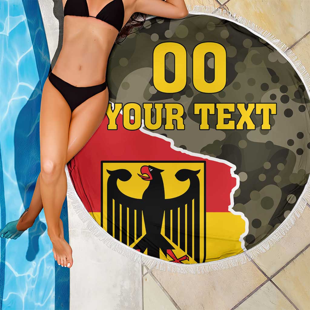 Round beach blanket with fringe edge, green camo and bold red-yellow coat-of-arms emblem