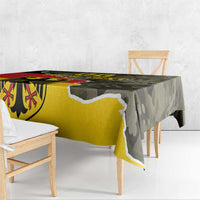 Rectangular tablecloth draped over dining table with bold coat-of-arms and camouflage print
