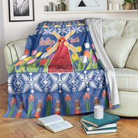 Blue Christmas blanket with windmill and tulip flower print, laid over a sofa chair.