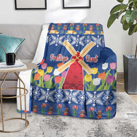 Blue Christmas blanket with windmill and tulip flower print, draped over a sofa bench.