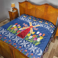 Blue quilt on bed with windmill cross, tulips, and snowflake pattern band.