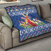 Blue quilt throw on sofa featuring windmill cross, tulips, and snowflake border.