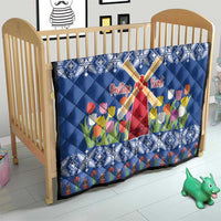 Blue quilt on crib mattress with windmill cross, tulips, and snowflake diamond quilting.