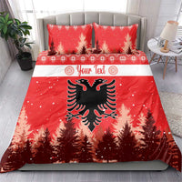 Red Christmas bedding set on bed with two matching pillows; eagle emblem and pine trees.