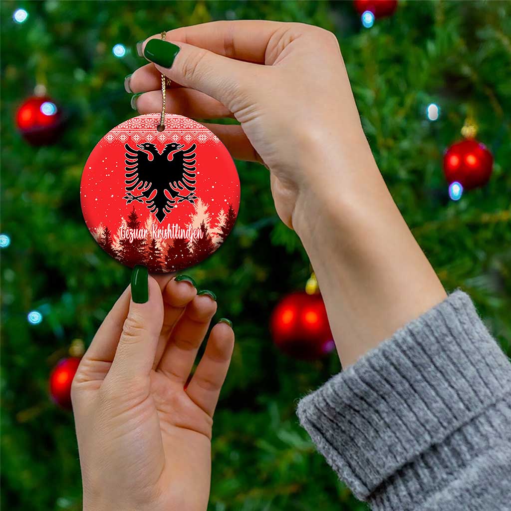 Red ceramic round ornament with double-headed eagle and personalized lettering, held by hand.