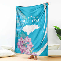 Personalized blue and white blanket with 'YOUR TEXT' held upright, floral orchids