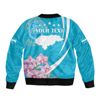 Blue bomber jacket back graphic with white map, pink orchids, and 'YOUR TEXT'; ribbed hem