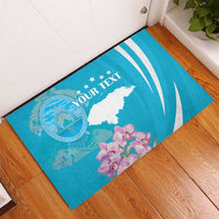 Blue rubber doormat with white map, orchids, and custom text on wood floor.