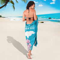 Blue personalized sarong with white waves, "YOUR TEXT" panel, and pink orchids at hem