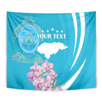 Blue tapestry wall hanging close-up with crest, stars, white map shape, and pink orchid flowers.