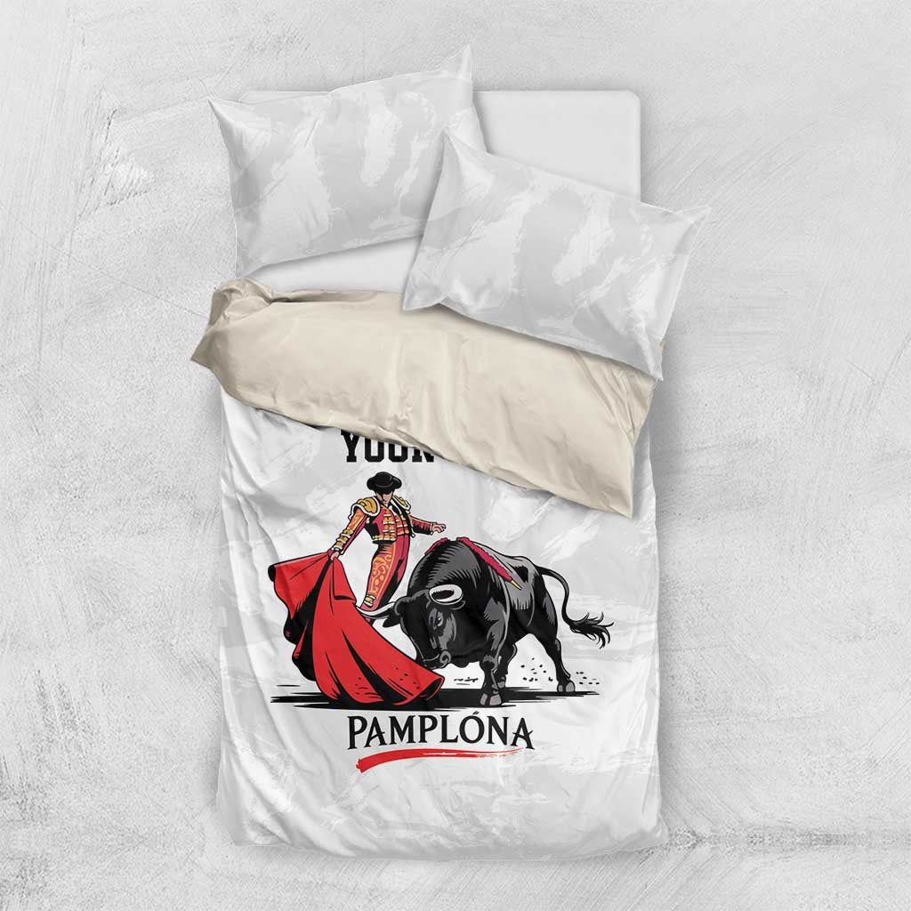 White bedding set laid flat with bull and matador print and 'PAMPLONA' text.