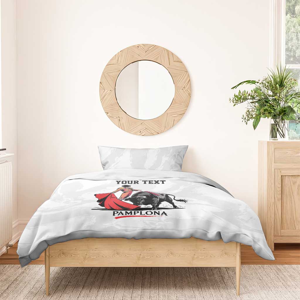 White bedding set with bull and matador artwork on duvet, 'YOUR TEXT' and 'PAMPLONA'.