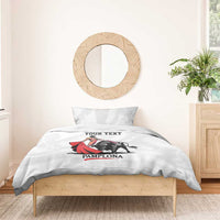 White bedding set with bull and matador artwork on duvet, 'YOUR TEXT' and 'PAMPLONA'.