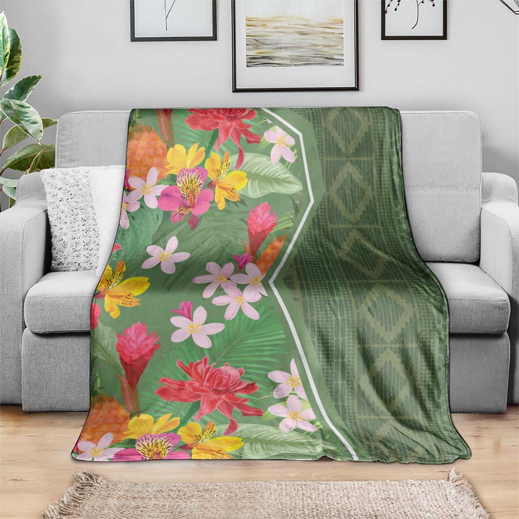 Green floral blanket draped on a sofa, featuring pink and yellow flowers with leaf motifs