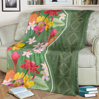 Green tropical flower blanket over a couch cushion, with multicolor blossoms and trim