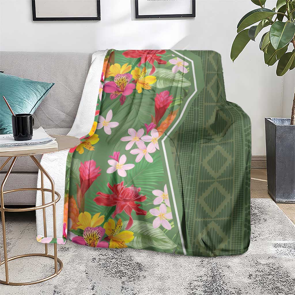 Green floral tropical blanket on a floor display, with pink, yellow, and orange flowers