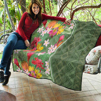 Green tropical floral quilt draped on sofa, multicolor blossoms with quilted diamond pattern
