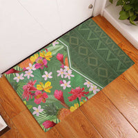 Green rubber doormat with tropical flower print and diamond pattern, placed by door