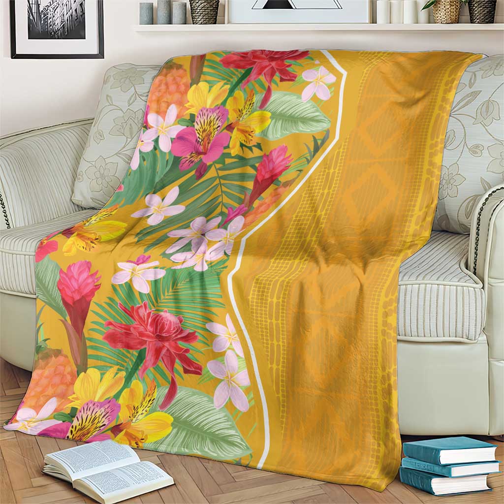 Yellow tropical flower blanket folded over a couch, bright floral print and solid yellow