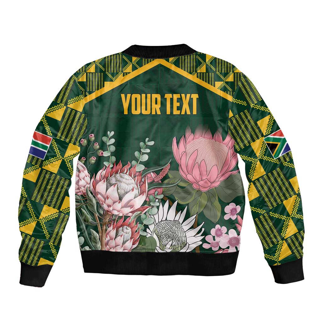 Green bomber jacket with kente-pattern sleeves, floral protea back, "YOUR TEXT" panel