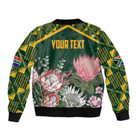 Green bomber jacket with kente-pattern sleeves, floral protea back, "YOUR TEXT" panel